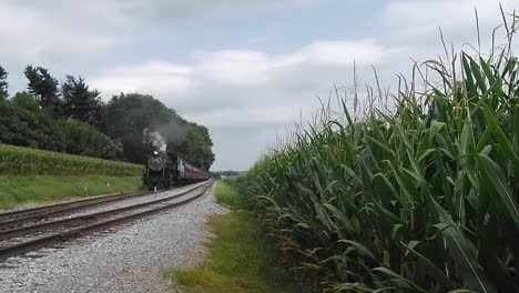 Tren-De-Vapor-Resoplando-A-Lo-Largo-De-Las-Tierras-De-Cultivo-Amish-Visto-Por-Un-Dron