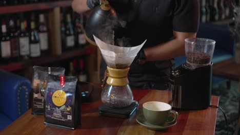 un uomo prepara il caffè con il metodo alternativo v60 versando acqua su chicchi di caffè filtrati, arrostiti e macinati