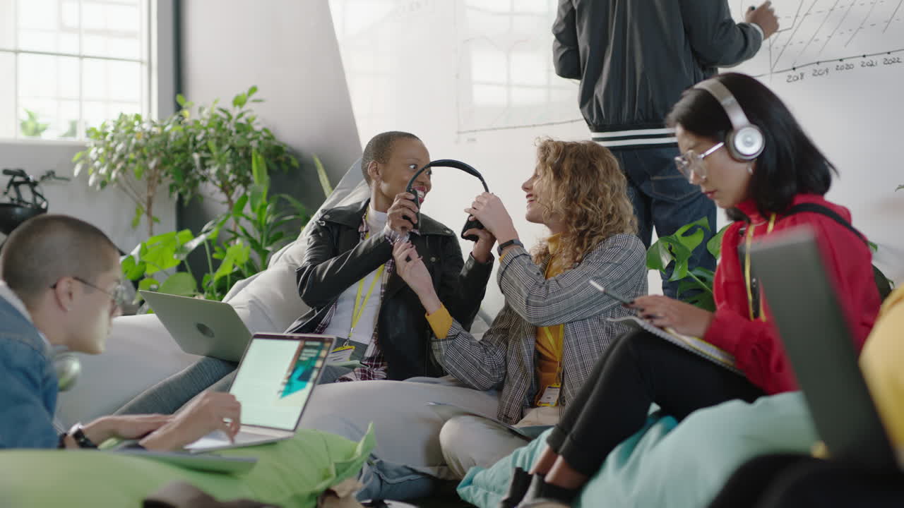 jóvenes empresarios creativos trabajando juntos amigos compartiendo auriculares escuchando música disfrutando de entretenimiento socializando en la oficina de moda workpalce