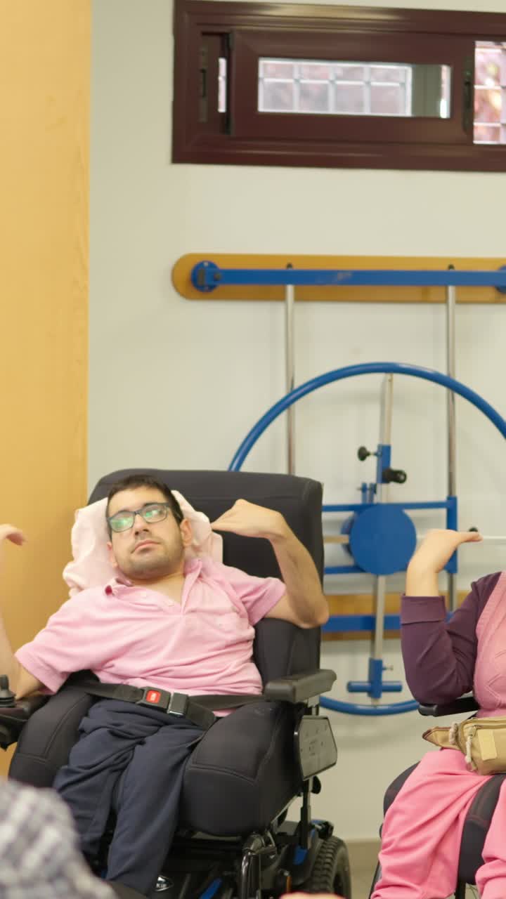 Adults in Wheelchairs Talking and Smiling in a Community Room
