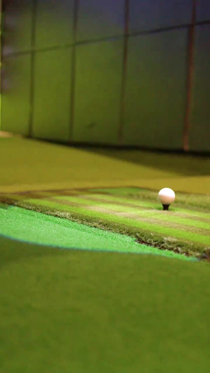 Una mazza da golf colpisce una palla da un tee all'interno di una struttura di simulazione virtuale ad alta tecnologia.