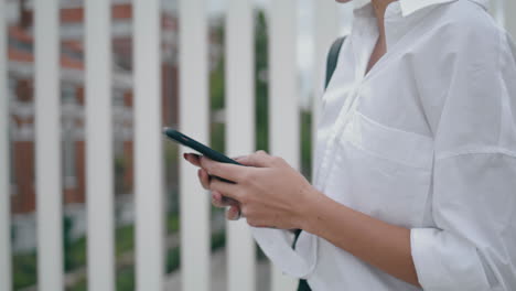 Die-Hände-Eines-Mädchens-Schreiben-SMS-Auf-Der-Straße,-Nahaufnahme.-Unbekannte-Frau-Scrollt-über-Ihr-Smartphone.