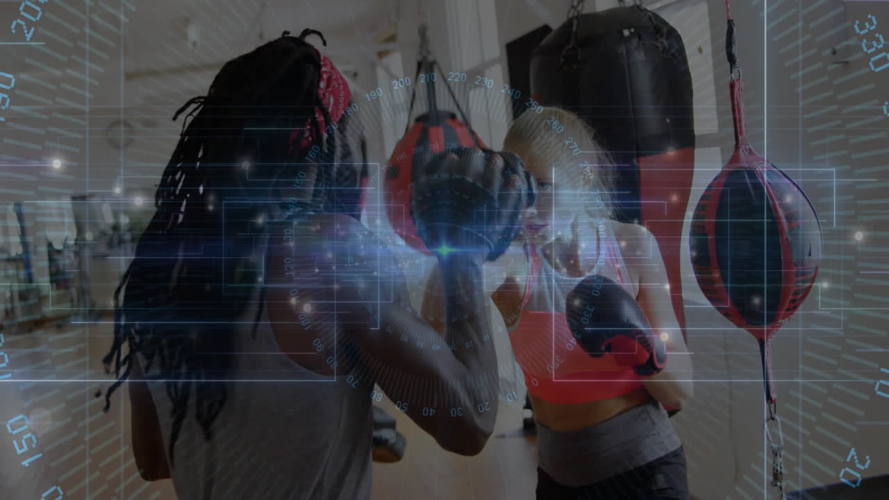 woman wearing pink sports bra punching focus mitt in gym, with animated workout graph overlay