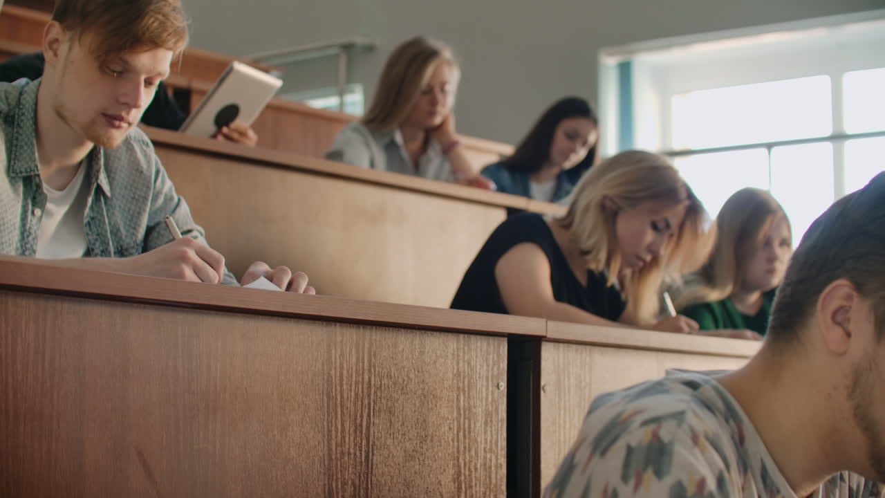 колледж текущая аудитория, в которой студенты слушают учителя и писать короткий фильм отчет в тетради. передавать знания и обучать студентов.