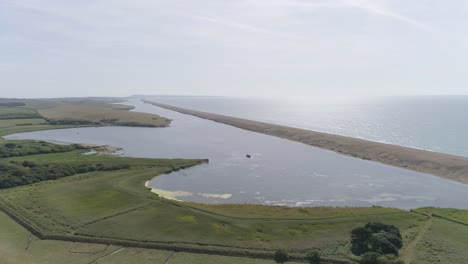 aerial tracking from right to left along chesil beach and the fleet lagoon rotating the shot out to sea and the oncoming sunshine