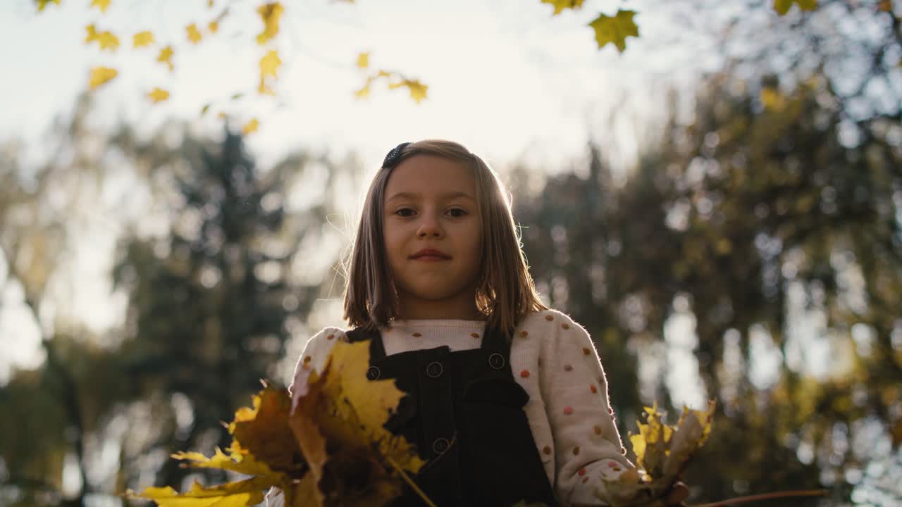 кавказская маленькая девочка играет с листом в парке