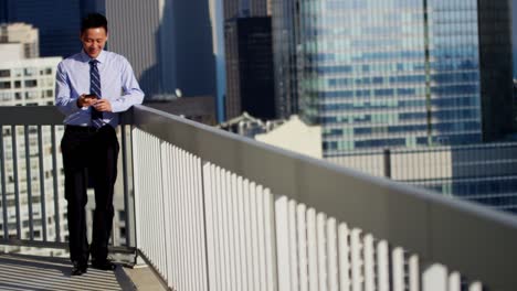 asian businessman working on rooftop using mobile technology