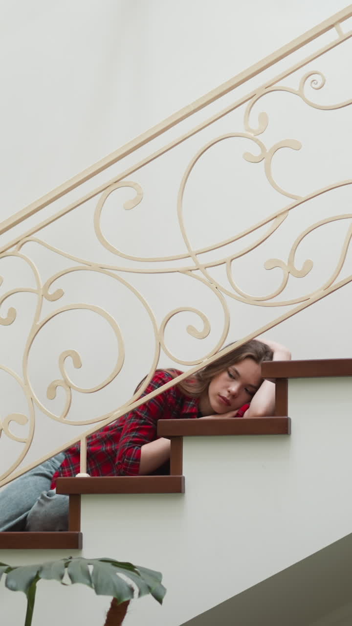 измученная женщина лежит на лестнице собственной квартиры. уязвимая женщина парализована сильной панической атакой дома. задумчивая женщина страдает от депрессивного расстройства