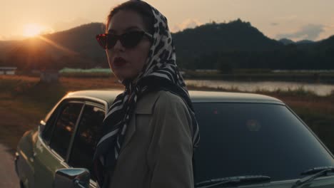 vintage woman by classic car at sunset