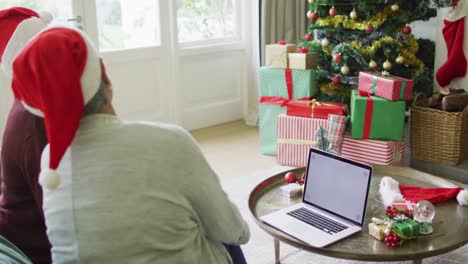 Two-happy-diverse-senior-woman-on-video-call-on-laptop-with-copy-space-at-christmas-time