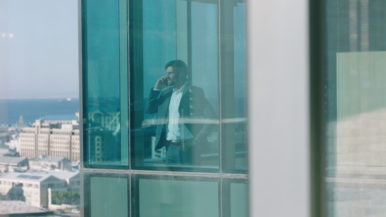uomo d'affari di successo che usa lo smartphone che fa una telefonata che discute di affari che guarda fuori dalla finestra dirigente aziendale che chatta sul cellulare che gestisce l'azienda 4k