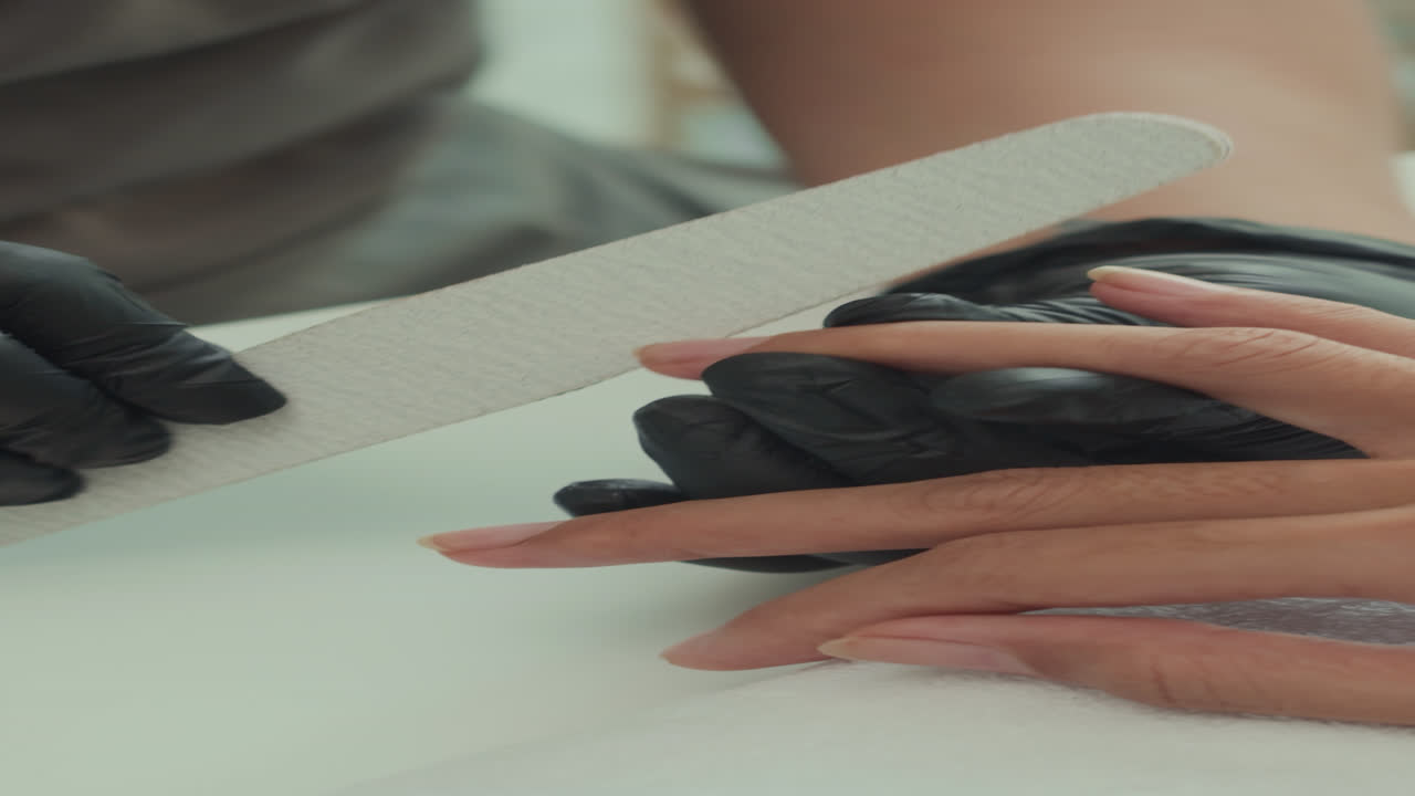 Vertical of Specialist Filing Nails of Woman at Salon