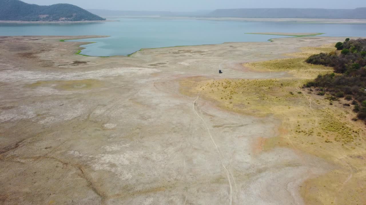 Aerial drone shot of an off roading jeep exploring a dried up lake reservoir at harsi dam in gwalior india