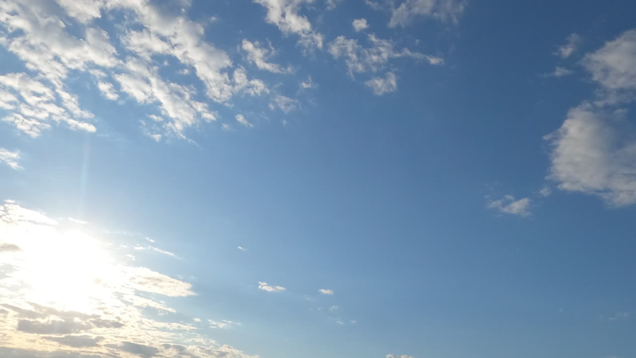 Light grey clouds soaring in the atmosphere slowly. Wind blows the clouds away and blue clear sky appears. Low angle view. Timelapse.