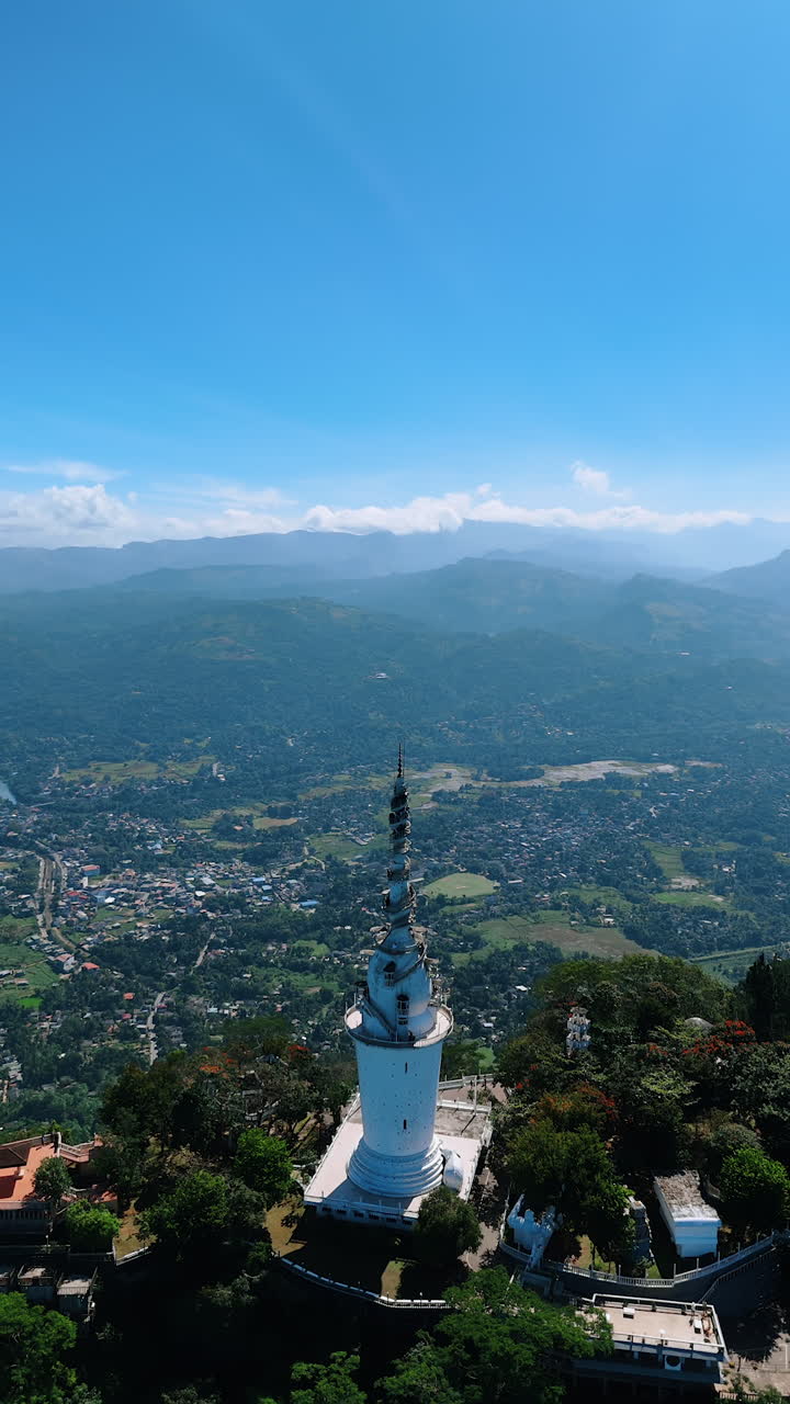 Beautiful Ambuluwawa Tower Temple on sunny day. Aerial perspective on the famous landmark revealing the view of Gampola Town Sri Lanka. Vertical video.