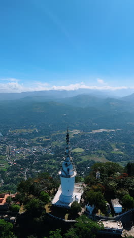 beautiful ambuluwawa tower temple on sunny day. aerial perspective on the famous landmark revealing the view of gampola town sri lanka. vertical video.