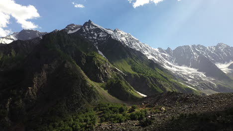 aerial shot of the mountains valley and sun rays coming through clouds at naltar valley in pakistan, epic rotating drone shot