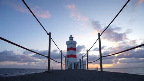 a view of the walkway towards a striking lighthouse in iceland just before sunset