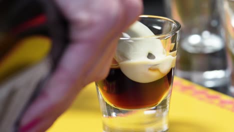 female barista making b-52 shot with layering technique