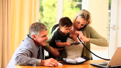 woman working at the desk and helping baby under her arm