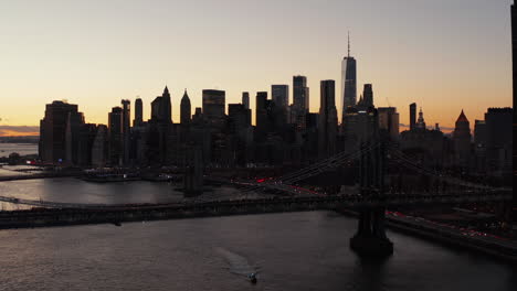 Breath-taking-romantic-shot-of-downtown-skyline-at-dusk.-Silhouettes-of-modern-skyscrapers-against-colourful-sunset-sky.-Busy-roads-around-river.-Manhattan,-New-York-City,-USA