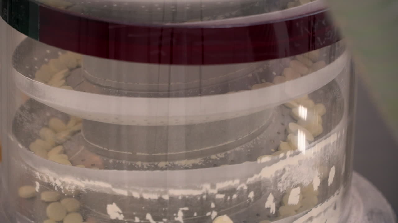 Pharma laboratory industrial machine circulates round drug pills, close up