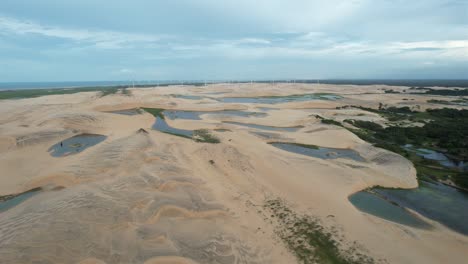 back-traveling-with-drone-amid-dune-and-lagoons-in-northeastern-brazil,-magical-sunset-light,-smooth-texture