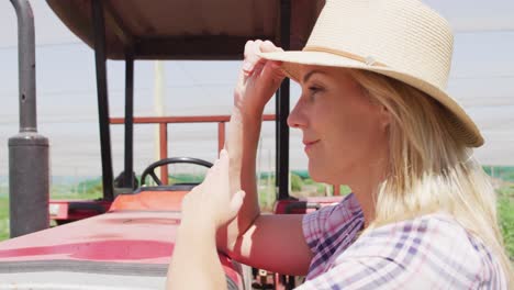 video of happy caucasian woman standing in front of tractor