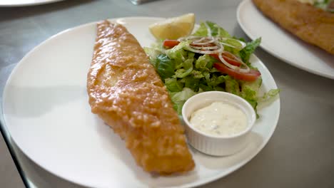 crispy fish served with fresh salad and tangy sauce in a cozy restaurant