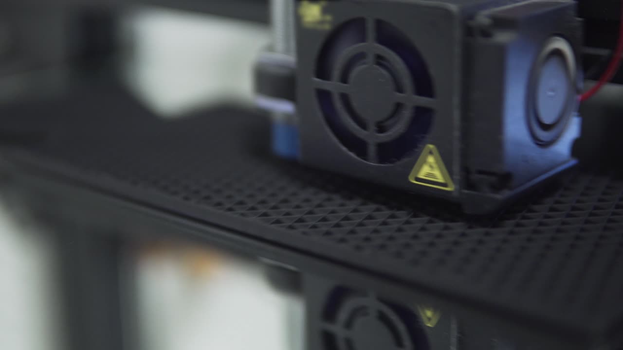 vista de cerca de una extrusora de impresora 3d fdm mientras trabaja en vidrio de espejo con filamento pla negro