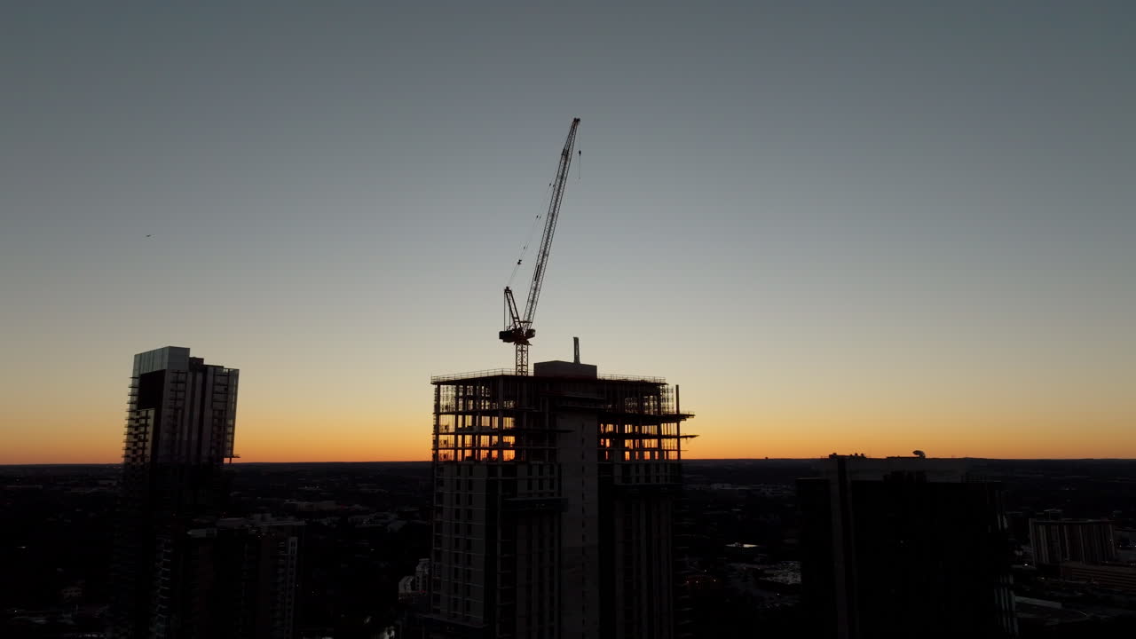 Crane silhouetted on top of skyscraper construction at sunset