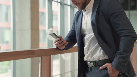 an attractive young, bearded businessman in a blue blazer consults his smart phone attentively