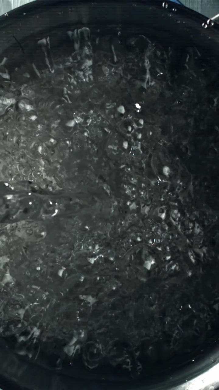 Close-Up View of Water Boiling in a Dark Pot