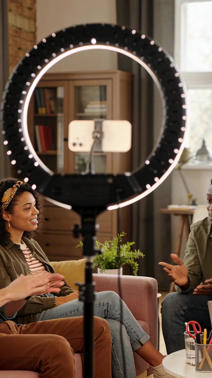 Vertical video: Lighting ring light starting recording, woman olive jacket talking with man at home