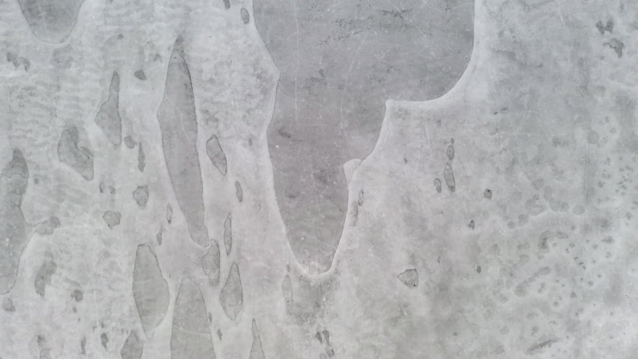 항공: 눈이 흐린 날에 얼음 주머니가 보이는 얼어붙은 호수 표면에 매우 낮고 가까이 날아가는 수직 드론