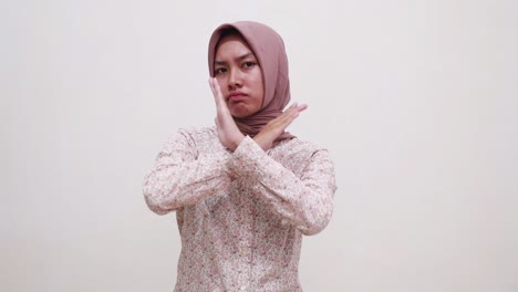 young asian muslim girl standing while making prohibition gesture with crossed hands