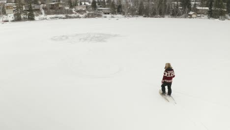 adult man in large fur hat, walks and plays in traditional snowshoes on frozen lake with his pet dogs in northern canada