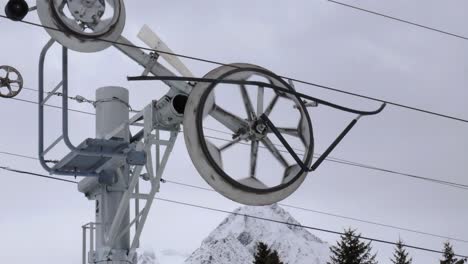 Primer-Plano-De-Una-Rueda-De-Telesilla-Que-Se-Mueve-Con-Un-Día-Nublado-Como-Telón-De-Fondo-De-Montaña-4k