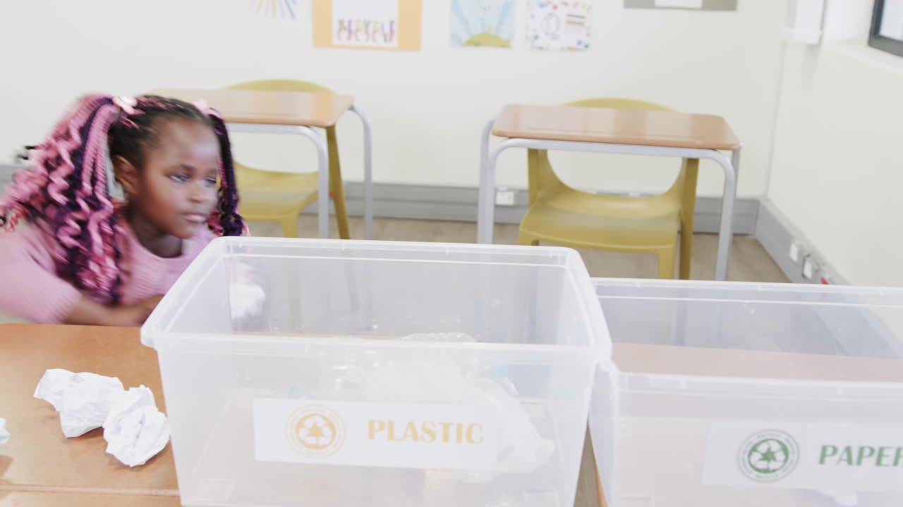 In school, girl sorting recyclables into bin, learning about environment conservation
