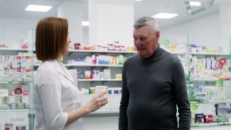 mujer joven hablando con un hombre mayor en la farmacia.