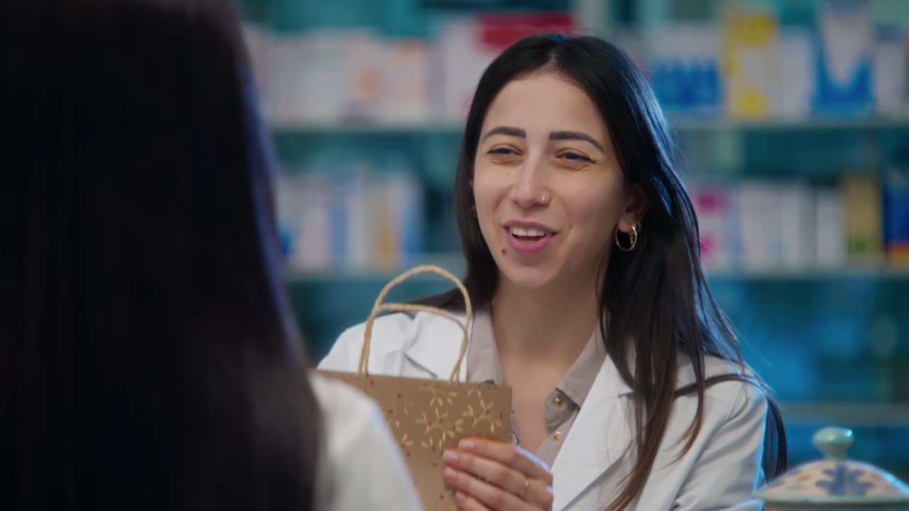 La farmacista sorride calorosamente mentre consegna prodotti confezionati a un cliente al bancone della farmacia