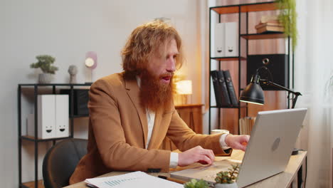 a man in a suit stretching at his desk in an office