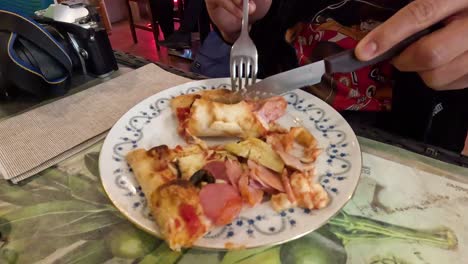 person enjoying pizza with fork and knife