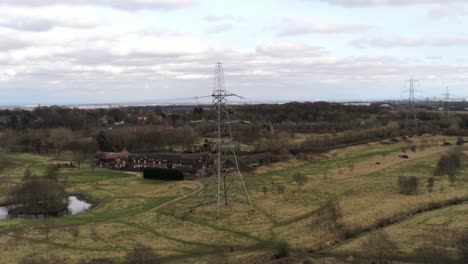 flying towards electricity distribution power pylon overlooking british parkland countryside