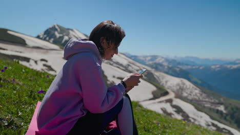 mujer usando el teléfono en la cima de una montaña
