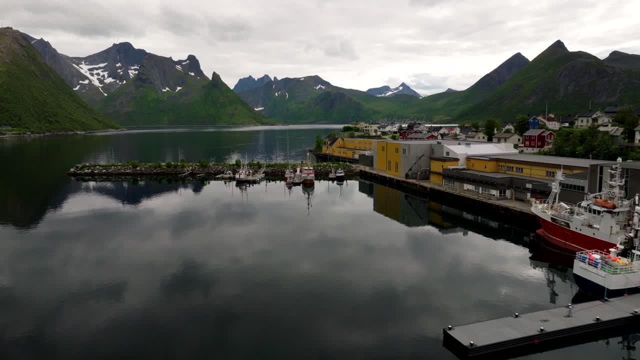 Husoy fishing village harbour with glassy calm water of Oyfjorden, Norway. Drone