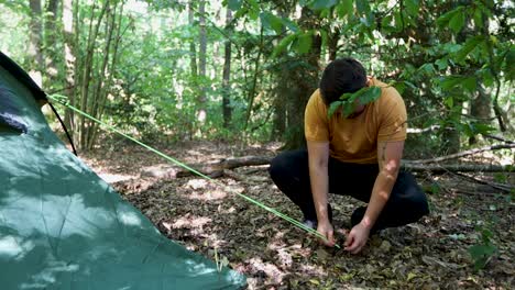 String-of-tent-snaps-while-young-man-trying-to-fix-it-to-ground,-slow-motion