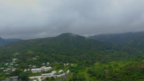 Disparo-Elevado-Que-Avanza-Sobre-Un-área-Urbana-Enclavada-En-Una-Exuberante-Vegetación-Tropical-Durante-Un-Día-Lluvioso