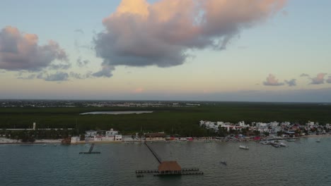 Drone-Above-Tiki-Hut,-Wooden-Jetty-into-Blue-Ocean