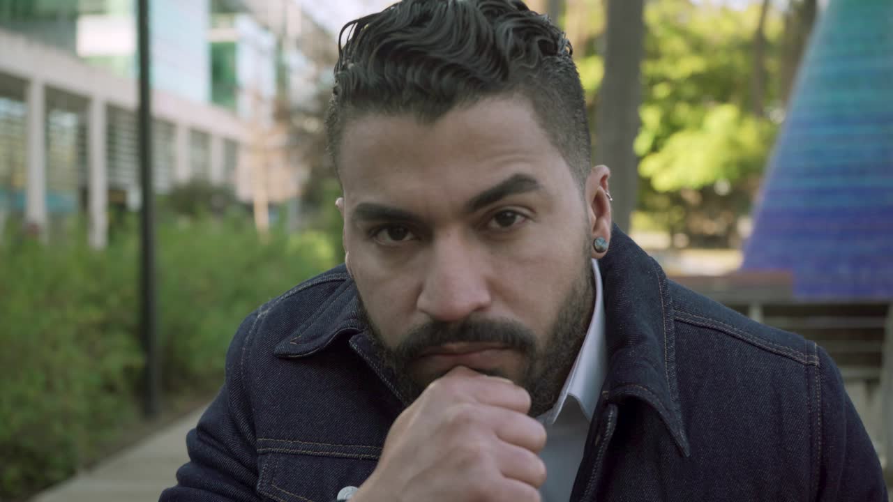 hombre con barba serio en chaqueta mirando a la cámara